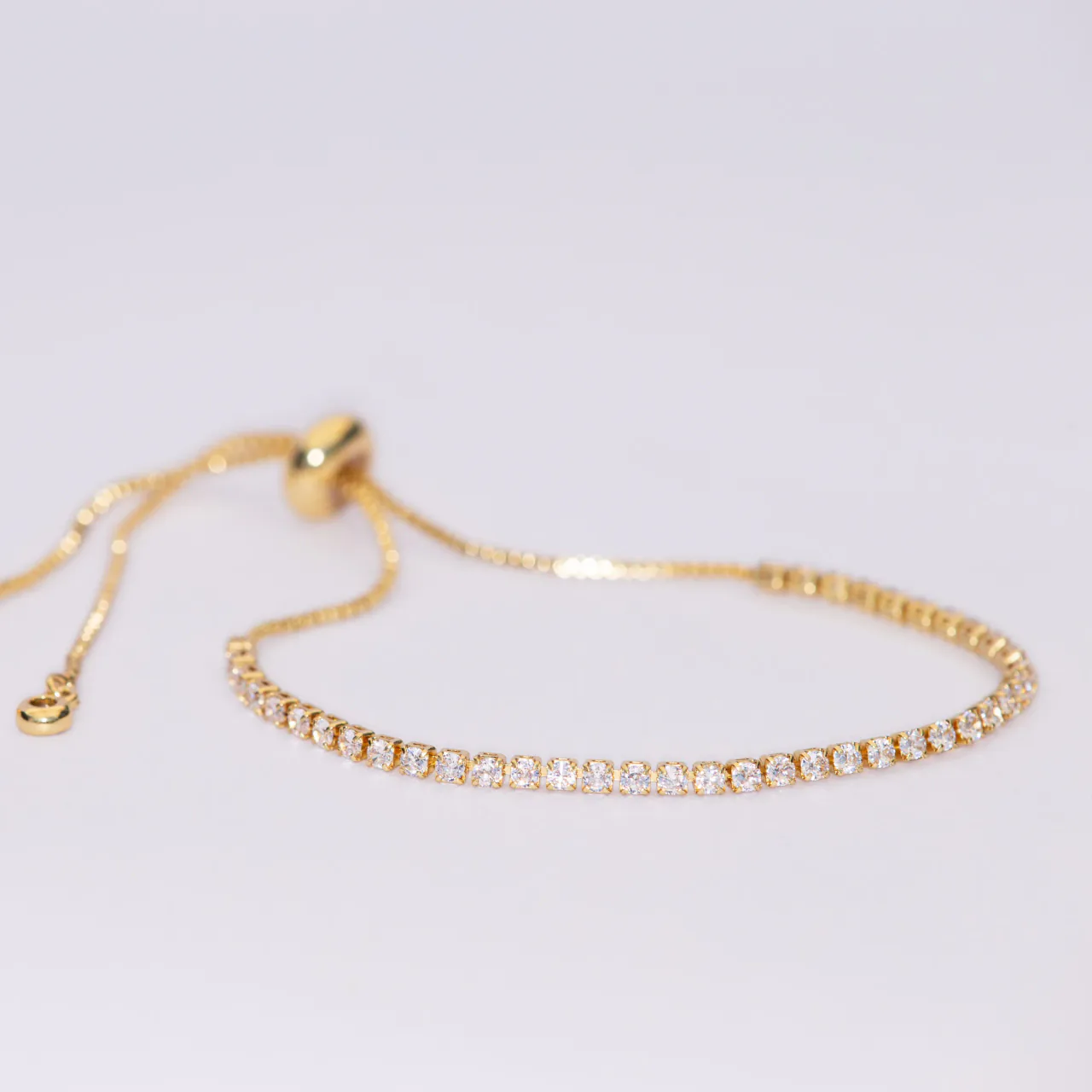 The Aria gold bracelet — a continuous line of stones on an adjustable slider chain