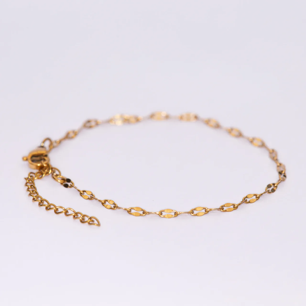 The Isa gold bracelet — a flat faceted mariner chain with an extender