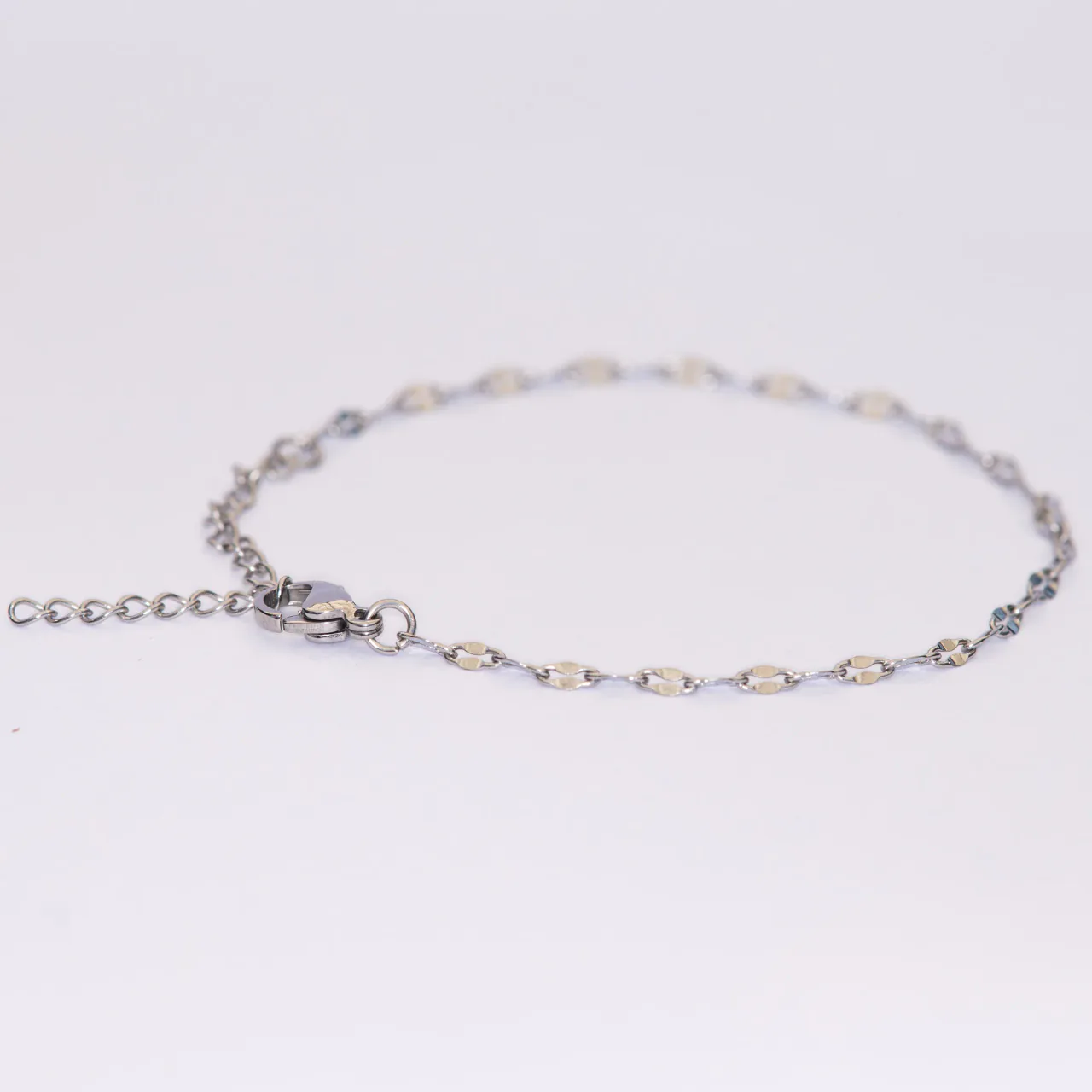 The Isa silver bracelet — a flat faceted mariner chain with an extender